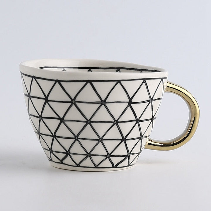 Kop med abstrakt geometrisk mønster og guldhåndtag