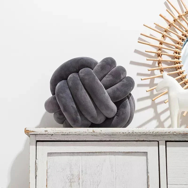 Dekorativ, blød pude med knyttet bold i suede look
