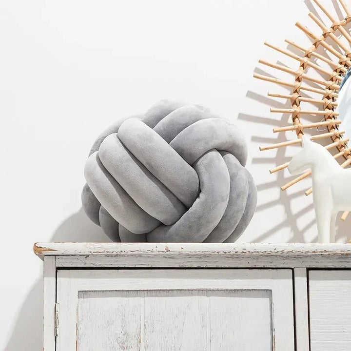 Dekorativ, blød pude med knyttet bold i suede look